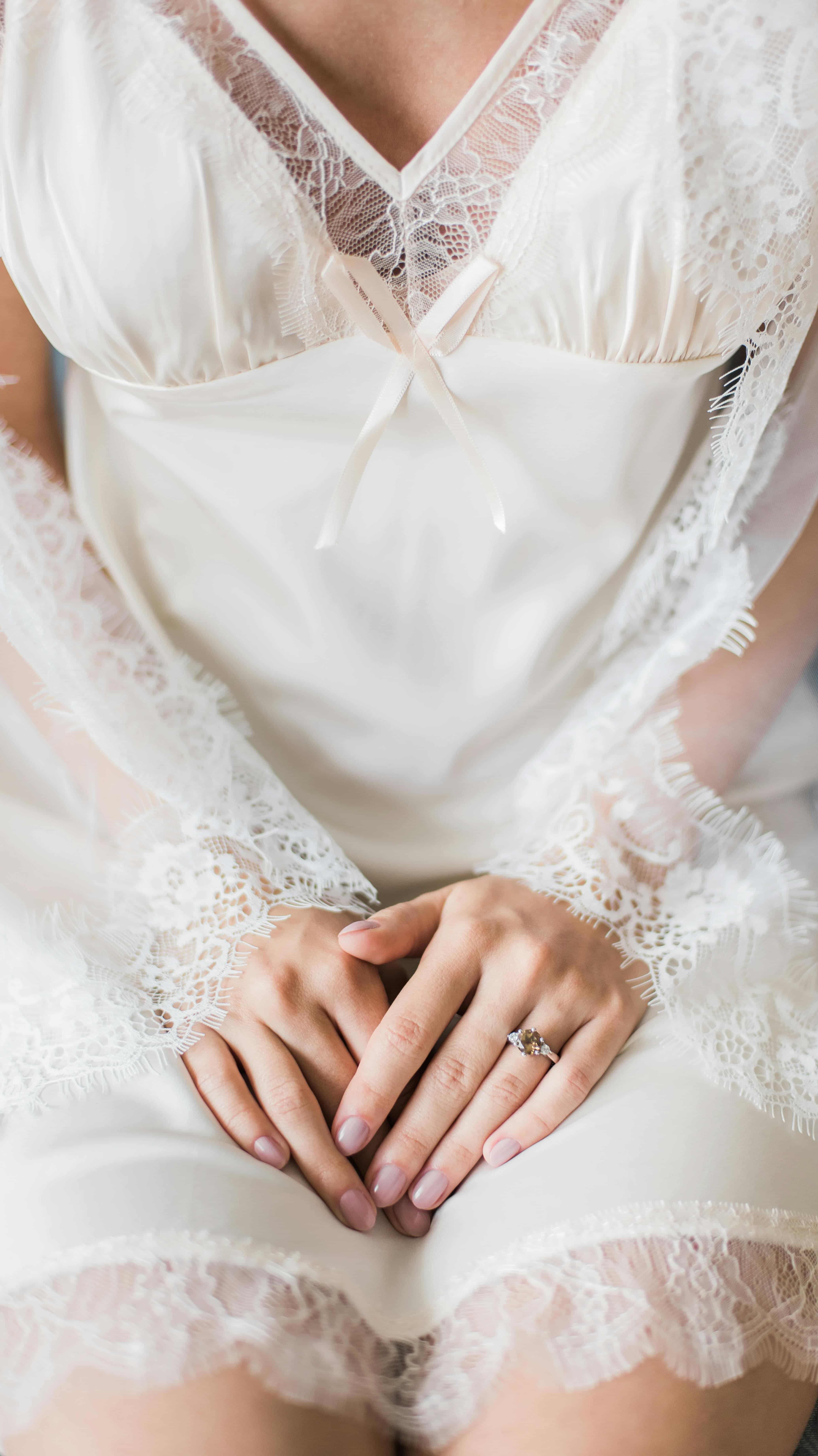Frau in Hochzeitskleid mit Händen in Schoß
